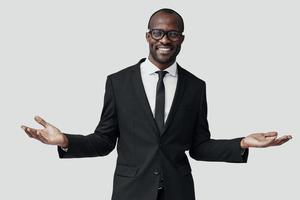 Happy young African man in formalwear looking at camera and smiling while standing against grey background photo