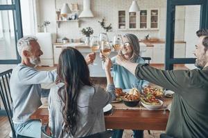 Happy multi-generation family toasting each other and smiling while having dinner together photo