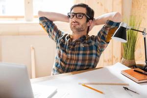 My space for inspiration.Handsome young man holding head in hands while sitting at his working place photo