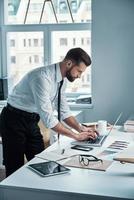 Confident young man in shirt and tie working with documents in office photo