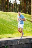 Man on his everyday jog. Full length of confident young man running along quayside photo