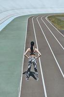 Queen of the track. Top rear view of young woman in sports clothing keeping hands on hips while standing on the running track photo