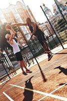 Jugando difícil. dos jóvenes con ropa deportiva jugando baloncesto mientras pasan tiempo al aire libre foto