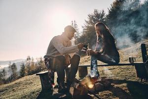 Happy young couple having morning coffee while camping in mountains photo