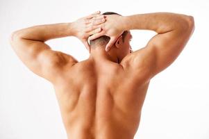 Showing his perfect body. Rear view of young muscular man posing while standing against white background photo