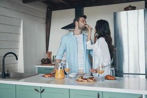 hermosa pareja joven degustando el desayuno mientras pasa tiempo en la cocina foto