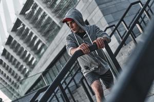 entrenando para el gran día. joven con ropa deportiva mirando hacia otro lado mientras hace ejercicio al aire libre foto