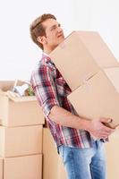 Too heavy boxes. Young man carrying the heavy boxes and expressing negativity while other cardboard boxes laying in the background photo