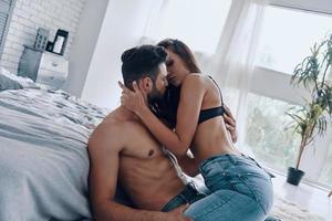 caliente y caliente. hermosa joven pareja semi-vestida a punto de hacer el amor mientras pasa tiempo en casa foto