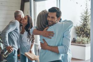 Cheerful senior parents meeting young couple inside the house photo