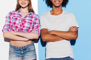 Style with the colorful attitude. Cropped picture of funky young couple smiling and keeping arms crossed while standing close to each other against colorful background photo