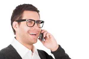 Good talk. Cheerful young man talking on the mobile phone and smiling while standing isolated on white photo