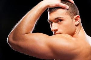 Strength and masculinity. Rear view of handsome young muscular man posing while standing against grey background photo