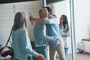 Happy senior parents meeting young couple inside the house photo