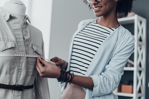 encaja perfectamente. primer plano de una joven africana que mide el pecho con cinta mientras está de pie en su taller foto