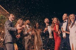 grupo de personas felices en ropa formal divirtiéndose junto con confeti volando por todas partes foto