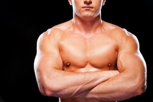 Strong man. Handsome young shirtless man looking up while standing against black background photo