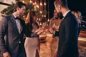 Group of people in formalwear toasting with champagne and smiling while spending time on luxury party photo