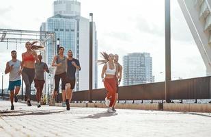 toda la longitud de la gente con ropa deportiva trotando mientras hace ejercicio en la acera al aire libre foto