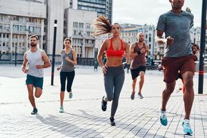 grupo de personas con ropa deportiva trotando mientras hacen ejercicio en la acera al aire libre foto