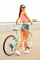 solo yo y mi bicicleta. vista trasera de una hermosa joven con nalgas perfectas caminando con su bicicleta y sonriendo foto
