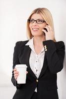 Coffee break. Confident mature businesswoman talking on the mobile phone and holding a coffee cup photo