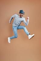 Full length of playful young man in casual wear shouting and gesturing while hovering against brown background photo