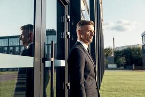 Confident mature businessman standing near office building outdoors photo