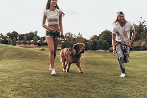 Happy to be together.  Full length of beautiful young couple playing with their dog while running in the park photo