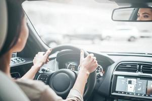 Focusing on driving. Rear view of attractive young woman in casual wear looking on the road while driving a car photo