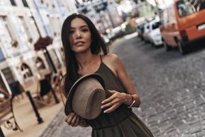 Best summer accessory. Attractive young woman holding her hat while standing outdoors