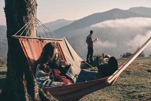 Feeling comfortable. Attractive young woman lying in hammock while camping with her boyfriend photo