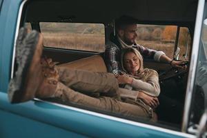 feliz de estar cerca. atractiva mujer joven descansando y sonriendo mientras su novio conduce una mini furgoneta de estilo retro foto