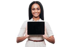 Copy space on her tab. Confident young African woman showing her digital tablet and smiling while standing against white background photo