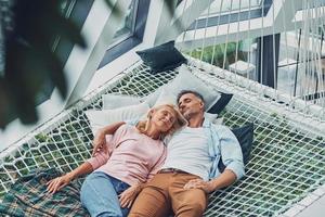 vista superior de una hermosa pareja madura durmiendo mientras se acuesta en una gran hamaca en casa juntos foto