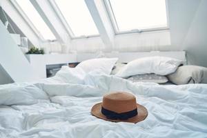 Image of hat laying on bed with pillows and nanket around photo