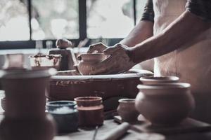 Creating something special. Close-up of man making ceramic pot on the pottery wheel photo