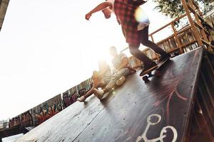 se siente como volar. jóvenes modernos patinando mientras pasan el rato con sus amigos al aire libre foto