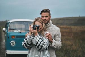 Great shot Beautiful young woman photographing and smiling while standing with her boyfriend outdoors photo