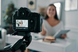 bloguear es su vida. hermosa joven gesticulando y sonriendo mientras hace un nuevo video para su blog foto