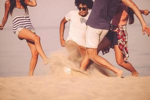 Active games on the beach. Cropped image of young people playing with soccer ball on the beach photo