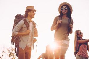 Nice day for hiking. Low angle view of young people with backpacks walking together and looking happy photo