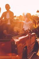 Enjoying perfect road trip. Beautiful young couple enjoying road trip while sitting in pick-up truck photo