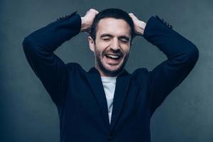 True happiness. Handsome young man keeping eyes closed and smiling while standing against grey background photo