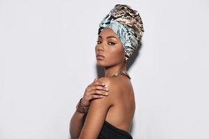 Simply stunning. Attractive young African woman in turban looking at camera while standing against grey background photo