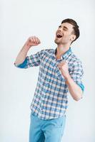 Happiness without limits. Cheerful young man in shirt gesturing and smiling while standing against white background photo