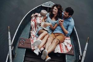 Made to be together. Top view of beautiful young woman reading book while sitting in the boat with her boyfriend photo