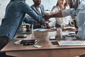 Successful team. Close up of a diverse group of business colleagues holding hands on top of one another in a symbol of unity while working in the board room photo