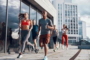 grupo de personas con ropa deportiva trotando mientras hacen ejercicio en la acera al aire libre foto