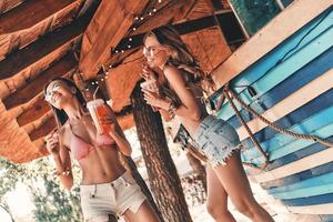 Just fun. Two attractive young women smiling and enjoying cocktails while dancing near the bar counter photo